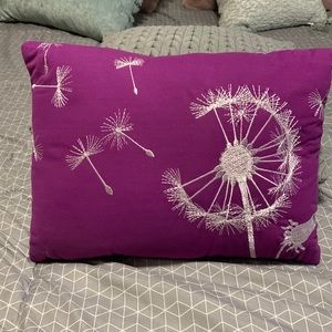Decorative pillow in bright purple with white stitching.